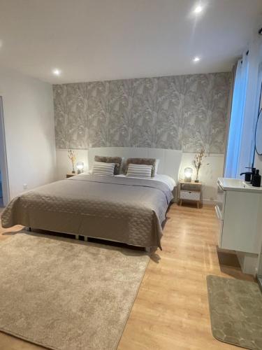 a bedroom with a large bed with a gray wall at Maison du Vignoble in Pfaffenheim