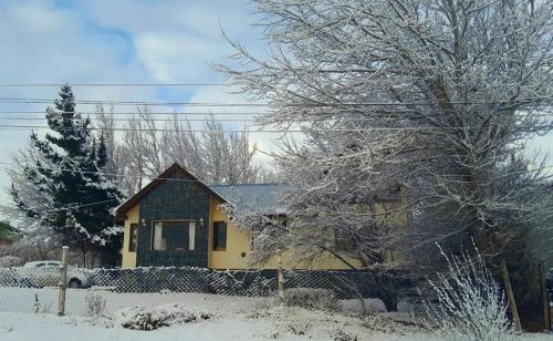 una casa gialla con neve per terra di Casa del Pino a El Calafate