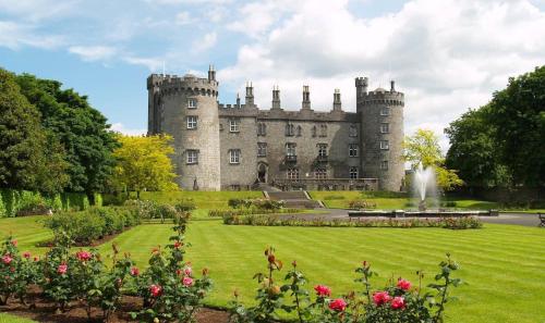 an old castle with a garden in front of it at The Tholsel Bar and Townhouse Kilkenny in Kilkenny