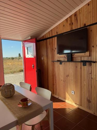 a room with a table and a tv and a red door at Cantinho Alentejano in Oriola