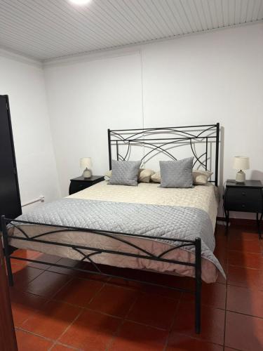 Un dormitorio con una cama negra con dos mesitas de noche. en Cantinho Alentejano, en Oriola