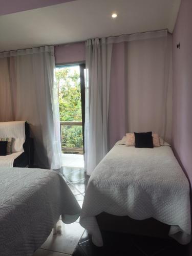 a bedroom with two beds and a window at Casa do aconchego k&P in Paraty