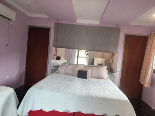 a bedroom with a large white bed with a window at Casa do aconchego k&P in Paraty