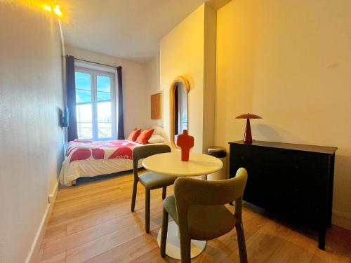 une chambre avec un lit, une table et des chaises dans l'établissement Suite Olney, à Lyon