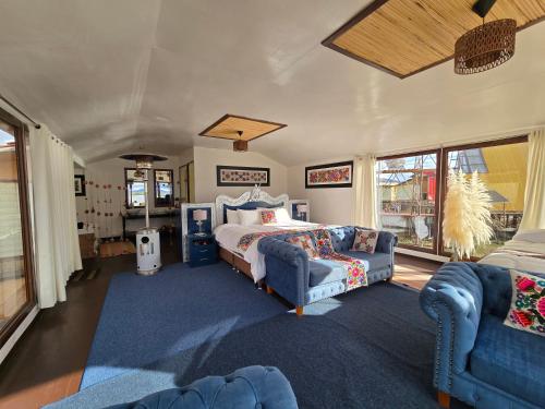 a bedroom with a bed and a couch and windows at Titicaca island lodge peru in Puno