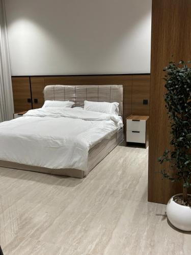 a bedroom with a white bed and a potted plant at شقة جديدة بغرفة وصالة in Al Kharj