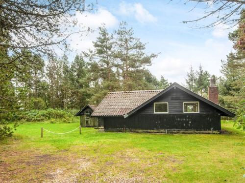 a black house in the middle of a field at 4 person holiday home in Oksbøl-By Traum in Oksbøl