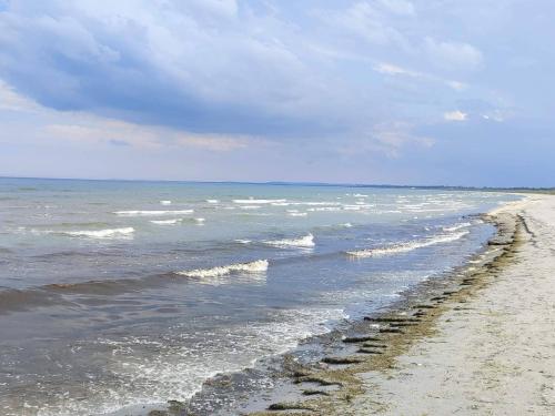 a sandy beach with waves coming in from the ocean at 4 star holiday home in Ålbæk in Ålbæk