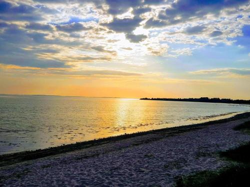 a beach with the sun setting over the water at 5 person holiday home in Sydals in Trænge