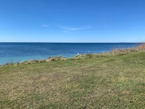 a field of grass with the ocean in the background at 6 person holiday home in Karrebæksminde-By Traum in Karrebæksminde