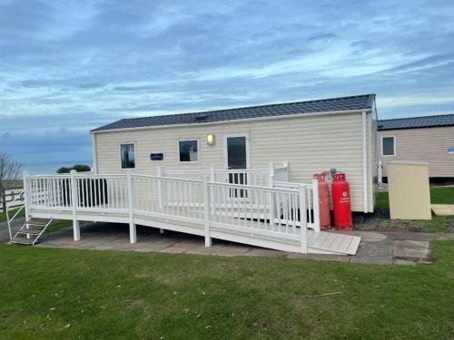 un mobile home avec une terrasse et une bouche d'incendie dans l'établissement Doniford Bay - Holiday Accommodation 20985, à Watchet