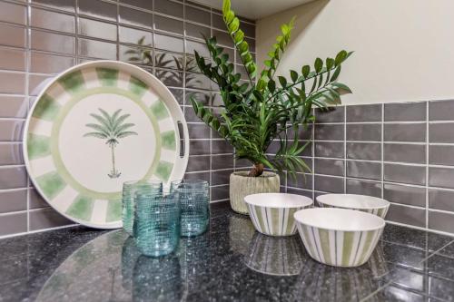 een tafel met vier kopjes, een bord en een plant bij Cairns 2BR Palms Stay Top Floor & Pool View in Westcourt