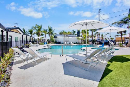 a pool with chairs and umbrellas in a yard at Pelican Post at Anna Maria Island Inn in Bradenton Beach