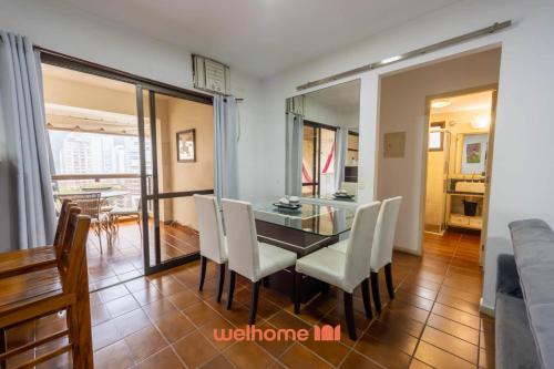 a dining room with a glass table and white chairs at Apto em Guarujá a 3 min a pe da Praia Pitangueiras in Guarujá