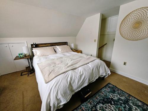 Un dormitorio con una cama con sábanas blancas y una alfombra. en MapleVilla, en Hancock
