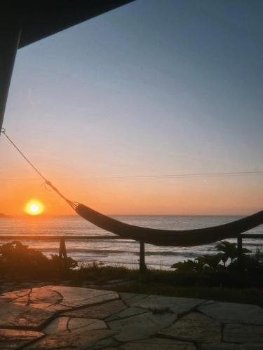 a hammock in front of the ocean at sunset at Hosteria CASA MILLER B&B FRENTE AL MAR in Bahía Mansa