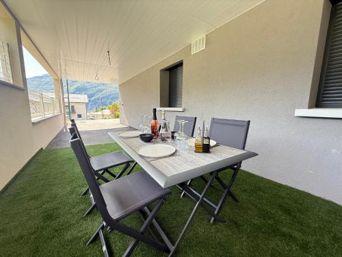 a table with chairs and wine bottles on it on the grass at Appartement Le Cosy Proche Station Ski - Piscine in Saint Avre la Chambre