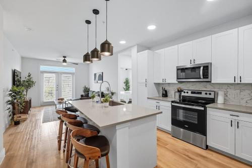 a kitchen with white cabinets and a island with bar stools at 412 Stylish 2B2B Resort Style Pool & Gym, Golf Simulator, 7M to Dickies Stadium, 15M to AT&T stadium in Fort Worth