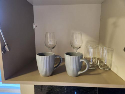 three wine glasses and cups on a shelf at Flat Serra fácil acesso a Savassi l Cozinha Completa l Novo l Área Nobre de BH in Belo Horizonte