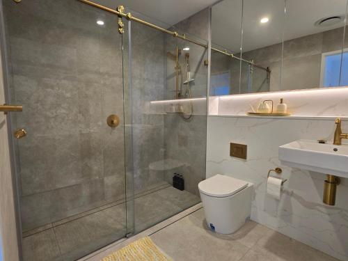 a bathroom with a shower and a toilet and a sink at Paramount Suite on Parkes Pool And City View in Sydney