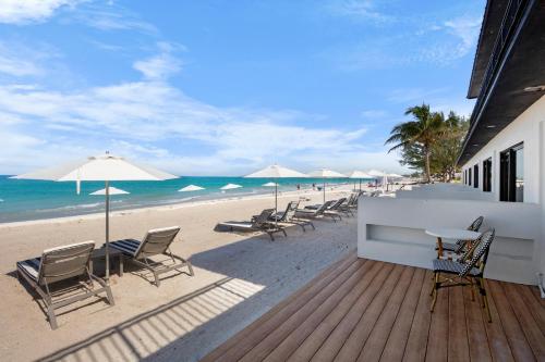 a deck with chairs and umbrellas on the beach at Seaside at Anna Maria Island Inn in Bradenton Beach
