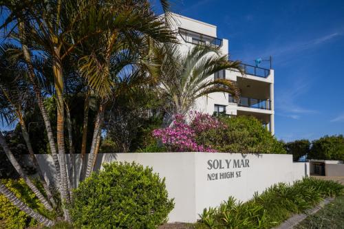 a building with a sign in front of a palm tree at Spectacular Sol y Mar @ Nambucca Heads in Nambucca Heads