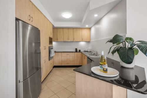 a kitchen with wooden cabinets and a stainless steel refrigerator at Spectacular Sol y Mar @ Nambucca Heads in Nambucca Heads