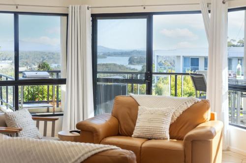a living room with a couch and large windows at Spectacular Sol y Mar @ Nambucca Heads in Nambucca Heads