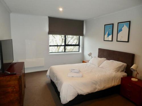 a bedroom with a large white bed with a window at The Peak 202 in Mount Buller