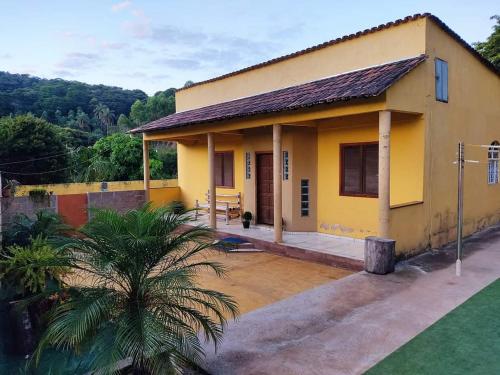 a yellow house with a palm tree in front of it at Sítio vida boa - Jambreiro in Itabira