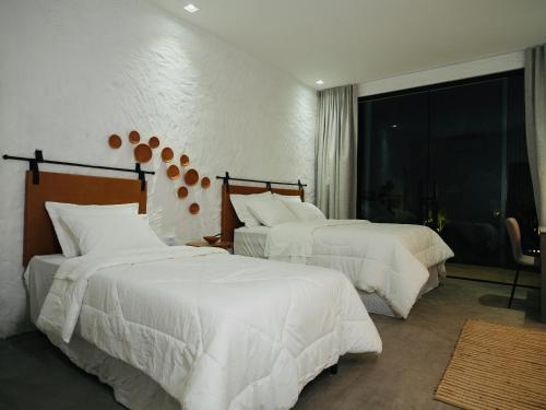 a bedroom with two beds with white sheets and a window at Vilarejo Casa Branca in Barreirinhas