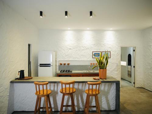a kitchen with a counter with three bar stools at Vilarejo Casa Branca in Barreirinhas