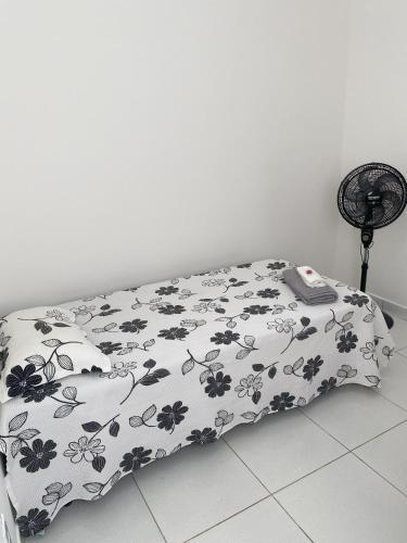 a bed with a black and white blanket on it at Apartamento dois quartos acolhedor prox Hospital Regional e Rodoviária in Santo Antônio de Jesus