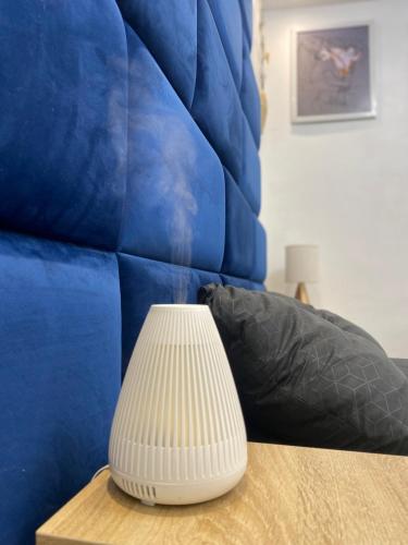a white vase sitting on a table next to a blue couch at Studio Jacuzzi in Montargis centre in Montargis