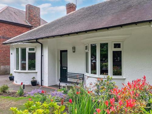 a white house with windows and flowers at North Lodge Cottage in Chester-le-Street