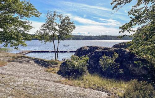 a large body of water with a tree and rocks at Nice Home In Edsbruk With Kitchen in Edsbruk
