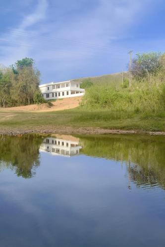 a house on a hill next to a body of water at Beira Rio Casa Canastra in Vargem Bonita
