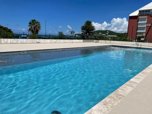 a swimming pool with blue water in front of a building at Studio Bougainvillier Style Bohème in Marigot