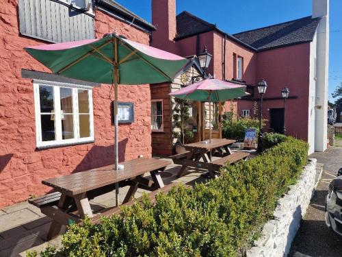 two picnic tables with umbrellas in front of a building at Barn Owl Inn in Newton Abbot