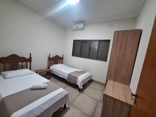 a hotel room with two beds and a window at Regente Feijó Centro in Regente Feijó