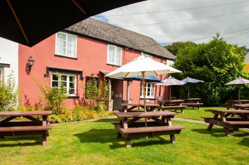 a group of picnic tables with umbrellas in front of a building at Barn Owl Inn in Newton Abbot