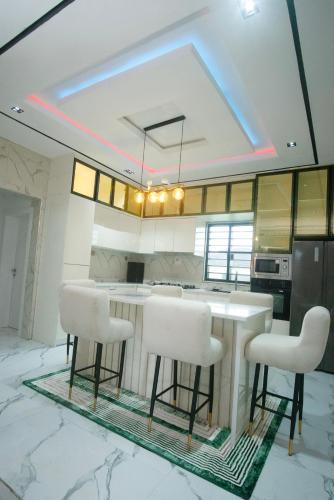 a kitchen with a table and some white chairs at Lily Luxury Home Shortlet Apartments 