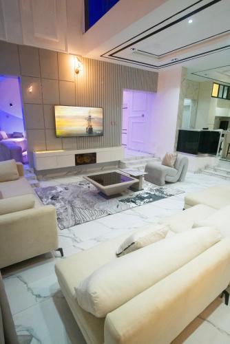 a living room with white furniture and a tv at Lily Luxury Home Shortlet Apartments 