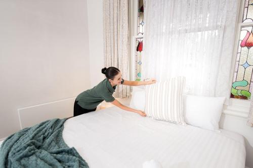 a woman sitting on a bed next to a window at Cathedral View - Sleeps 16 in Bendigo