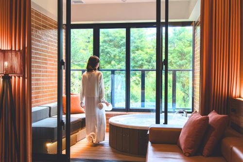 a woman standing in a bathroom with a tub at TWIN LINE HOTEL YANBARU OKINAWA JAPAN Formerly Okinawa Suncoast Hotel in Nago