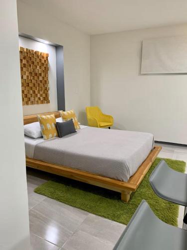 a bedroom with a bed and a yellow chair at Acogedora suite con entrada independiente in Minatitlán