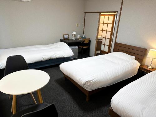 a room with two beds and a table and a desk at RONENAI BASE in Biei