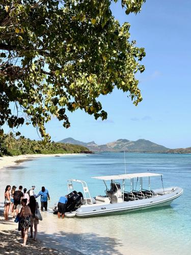 a group of people on a beach next to a boat at Blue Lagoon Beach Resort in Nacula Island