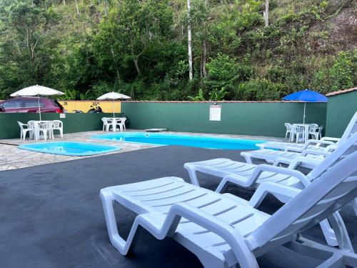 een groep witte ligstoelen naast een zwembad bij Flats e Apartamentos Temporada Mar Brasil in Ubatuba