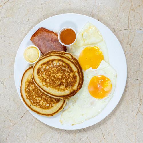 a plate of breakfast food with eggs and sausage at Muna Hotel in San Pedro Sula